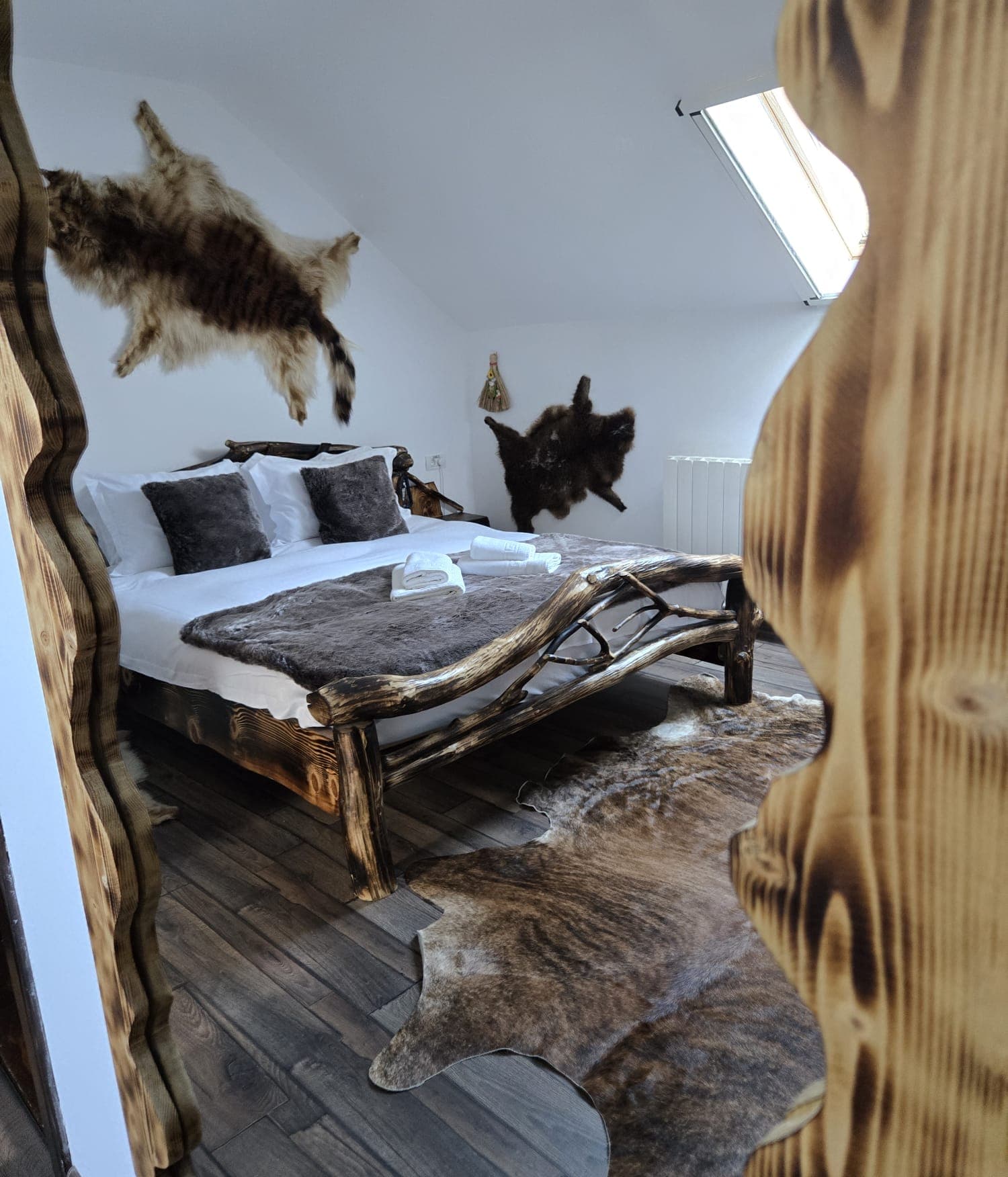Dormitor rustic la mansardă cu pat din bușteni și blănuri decorative