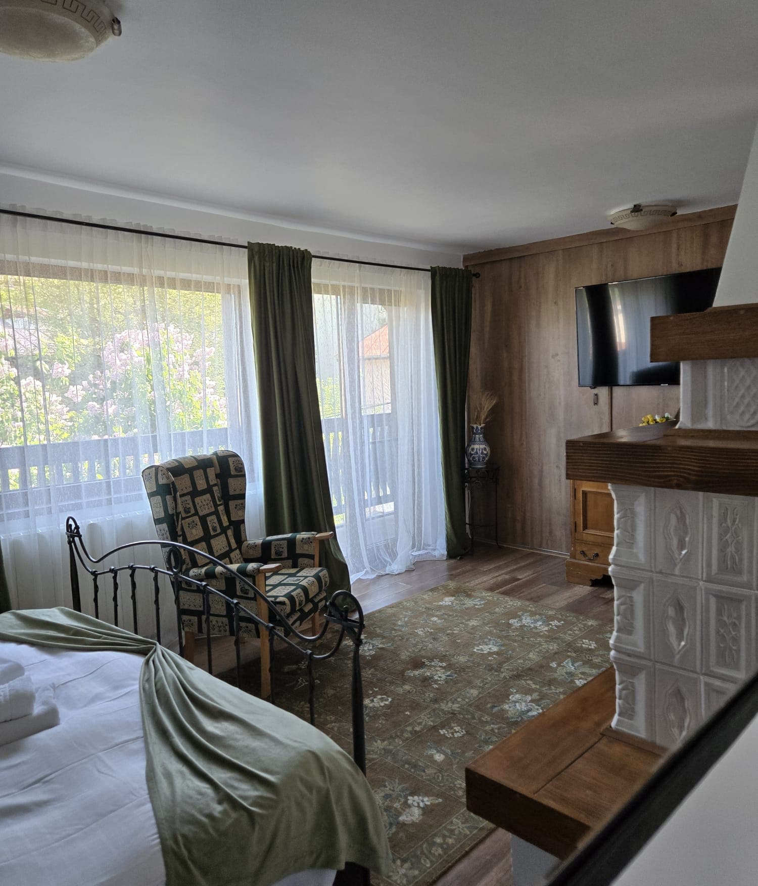 Dormitor cu accente verzi, sobă de teracotă și ieșire la balcon